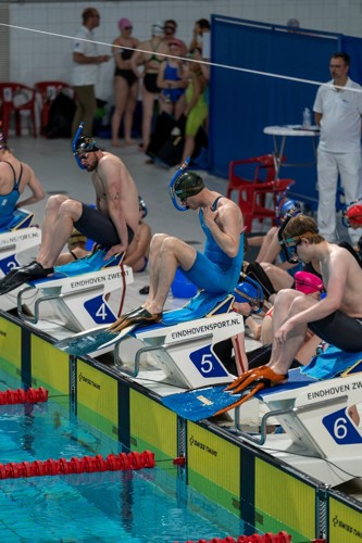 Vinzwemmers zittend op het startblok voor een wedstrijd