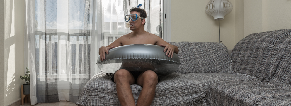 Man zit met zilveren zwemband en snorkel in de mond op hoekbank