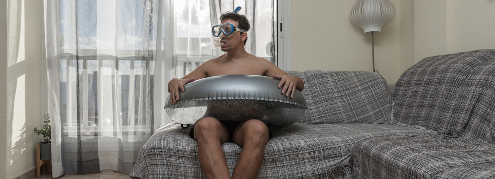 Man zit met zilveren zwemband en snorkel in de mond op hoekbank