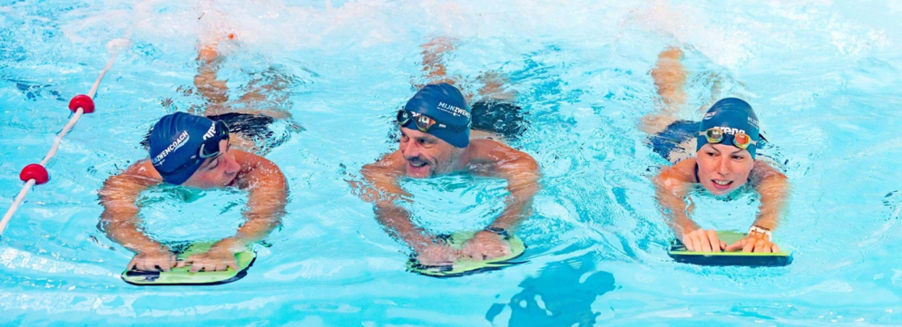 Drie zwemmers zwemmen benen met een zwemplankje