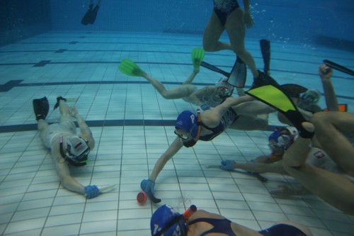 Onderwaterhockeyers die de puck spelen in een wedstrijd